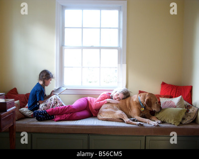 Un enfant se trouve au sommet du chien pendant que l'autre lit un livre, baigné dans une lueur éthérée, Esprit Saint ou juste un truc de la lumière ? Banque D'Images