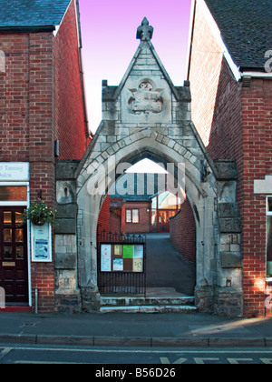 Bordée de propriétés commerciales en brique rouge, une arche en pierre avec porte en fer forgé à l'entrée d'un lieu religieux. Avantage. Oxon Banque D'Images