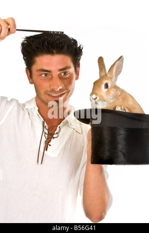 Jeune Magicien tenant sa baguette magique sur un lapin dans un chapeau haut Banque D'Images