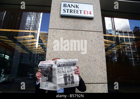 Travailleur dans Bank Street, Canary Wharf, London se lit les dernières nouvelles financières moroses Banque D'Images