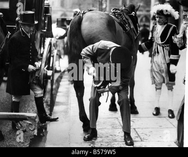 Lord Mayor's Show Incident à l'extérieur du palais de justice : Blossom, l'un des principaux chevaux dimensions le maire sortant, l'entraîneur a amené son sabot arrière vers le bas sur le trottoir à l'extérieur du palais de justice en tirant sa chaussure, sans le sabot. Deux maréchaux-ferrants, l'un de l'un des maîtres nageurs et des Royal Horse Guards, les saignements ont cessé sur le pouce, a pris la vieille chaussure off, et re-chausser le cheval sur le trottoir, quelques minutes avant la procession a dû quitter le palais de justice. Mettre la dernière main à la raquette de fleurs sur le trottoir devant le palais de justice. Novembre 1956 P004864 Banque D'Images