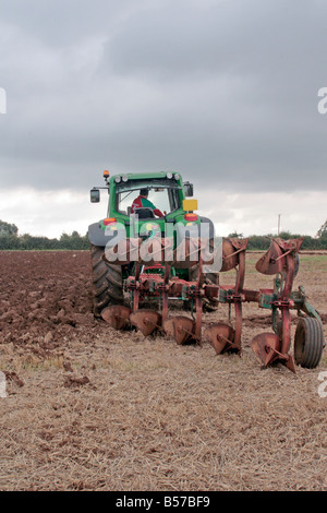 Agriculteur britannique à l'œuvre de labourer son champ à l'aide d'une charrue réversible. Banque D'Images