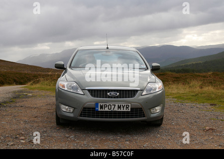 Ford Mondeo garée sur bord avec chauffeur derrière la roue avec des montagnes en arrière-plan de Grampian Ecosse UK Banque D'Images