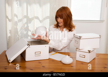 Red haired woman 40 -50 ans organise des objets dans la chambre Banque D'Images