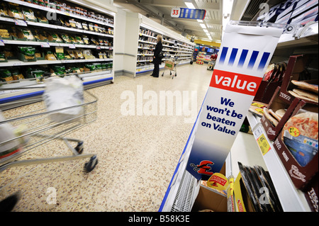 Tesco Value : un homme d'affaires avec panier marchant dans une allée de réfrigérés pizza et pâtes. Banque D'Images