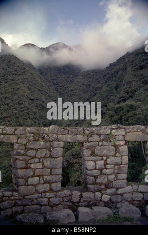 Photo panoramique des nuages du matin couvrant les montagnes au-delà des ruines de Winay Wayna sur la piste Inca au Pérou. Banque D'Images