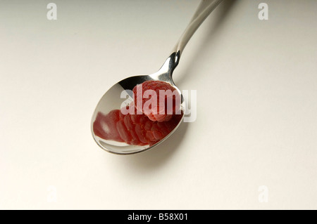 Cuillère en argent avec un fresh red berry framboise sur fond blanc il l'éclairage studio Banque D'Images