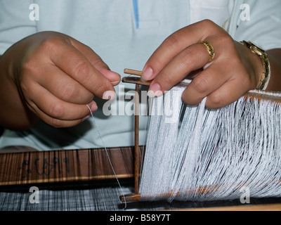 Travailler avec les doigts sur un métier de la soie en Thaïlande Korat Banque D'Images