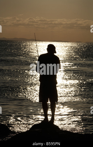 L'homme silhouette personne pêche en mer dans la lumière du soir coucher du soleil à Amity Point sur North Stradbroke Island Queensland QLD Australie Banque D'Images