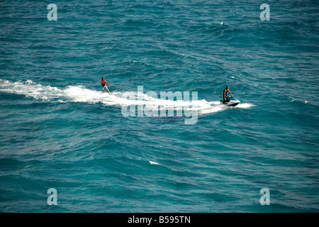 Waterskier sur planche de surf ski nautique tracté par l'homme sur le jet ski en mer au large de l'Île Stradbroke-nord Queensland QLD Australie Banque D'Images