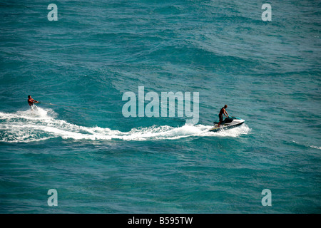 Waterskier sur planche de surf ski nautique tracté par l'homme sur le jet ski en mer au large de l'Île Stradbroke-nord Queensland QLD Australie Banque D'Images