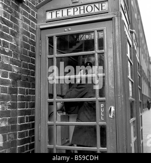 L'homme à l'aide d'une cabine téléphonique. Le téléphone rouge fort a été conçu par Sir Giles Gilbert Scott, et jusqu'au début des années 1980 a été un spectacle familier dans les rues du Royaume-Uni, Malte et Gibraltar, et en dépit d'une diminution de leur nombre au cours des dernières années, les cases en rouge sont encore visibles dans de nombreux endroits. La couleur rouge a été choisie pour les rendre faciles à repérer. Avril 1975 75-1871 Banque D'Images