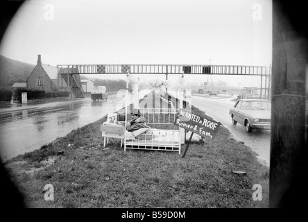 Romeo Meli accroupi contre la pluie battante dans un lit comme les camions de le percer à jour passé. C'est une sieste sur l'herbe de la division d'une double voie de chariot dans une tentative de sauver son vouée cottage. Il est le dernier homme de gauche regrettent la disparition de la déserté de Groes près de Port Talbot, Glam. Les 21 autres familles ont déjà quitté disparu. Avril 1975 75-1947-001 Banque D'Images