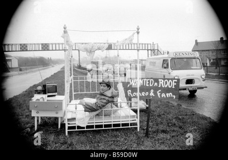 Romeo Meli accroupi contre la pluie battante dans un lit comme les camions de le percer à jour passé. C'est une sieste sur l'herbe de la division d'une double voie de chariot dans une tentative de sauver son vouée cottage. Il est le dernier homme de gauche regrettent la disparition de la déserté de Groes près de Port Talbot, Glam. Les 21 autres familles ont déjà quitté disparu. Avril 1975 75-1947-002 Banque D'Images