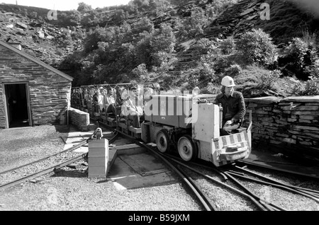 L'industrie minière : : 'Britain's Beauty Spot plus laid' : Blaenau Ffestiniog, un village de mineurs d'ardoise galloise, où les chefs des scories giat tour Ardoise haut au-dessus des toits et plonger jusqu'aux portes des maisons, est devenu une des principales attractions touristiques. Plus de 2 000 touristes par jour troupeau de faire une visite guidée autour de la mine d'Ardoise de Llechwedd - menées par les mineurs, les mêmes hommes qui avaient l'habitude d'une griffe peu dangereux et vivre de la montagne lors de l'extraction de l'ardoise est à son apogée. Evan Richards, 63 le off avec un autre chargement de train de touristes autour de la mine Banque D'Images