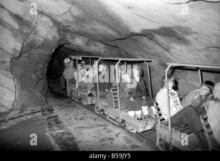 L'industrie minière : : 'Britain's Beauty Spot plus laid' : Blaenau Ffestiniog, un village de mineurs d'ardoise galloise, où les chefs des scories giat tour Ardoise haut au-dessus des toits et plonger jusqu'aux portes des maisons, est devenu une des principales attractions touristiques. Plus de 2 000 touristes par jour troupeau de faire une visite guidée autour de la mine d'Ardoise de Llechwedd - menées par les mineurs, les mêmes hommes qui avaient l'habitude d'une griffe peu dangereux et vivre de la montagne lors de l'extraction de l'ardoise est à son apogée. Chargement d'un train de touristes dans la mine. Septembre 1975 75-04947-010 Banque D'Images