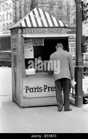 Un journal du matin reader prend son papier à partir d'un kiosque dans le 15ème arrondissement de Paris, France. ;Avril 1975 ;75-2079-007 Banque D'Images