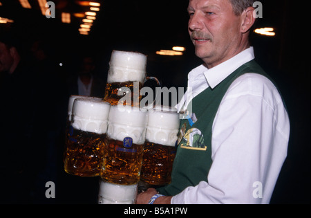 Annuel Oktoberfest beer festival hall immense plafond Lumières Waiter man steins plein litre bière, MUNICH ALLEMAGNE Banque D'Images