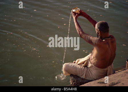 Pèlerin hindou verser de l'eau de dieux sages ou l'âme des défunts Varanasi Uttar Pradesh Inde Asie Banque D'Images