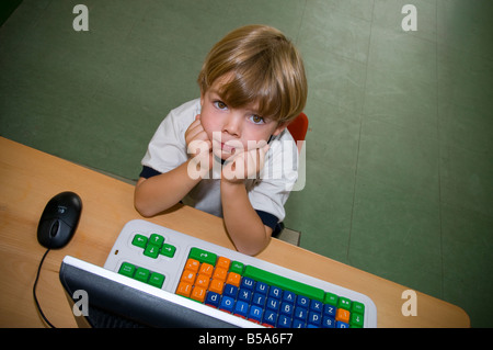 Garçon enfant en maternelle recherche à partir de son clavier d'ordinateur studies Banque D'Images