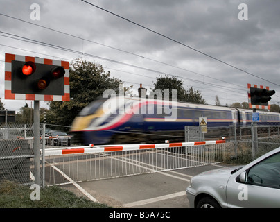 Voitures attendant à un passage à niveau pour une vitesse élevée train pour passer Banque D'Images