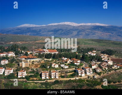 Maisons et stadium dans la ville de Metula en Haute Galilée, avec le Mont Hermon couvert de neige en arrière-plan, Israël, Moyen Orient Banque D'Images