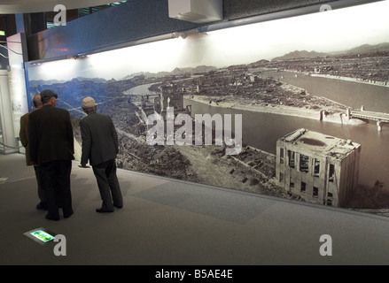 Les visiteurs qui cherchent à l'énorme mur affiche montrant la destruction de la ville, après la bombe atomique, Hiroshima, Honshu, Japan Banque D'Images