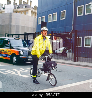 Un ouvrier de bureau cycliste cycliste pour travailler sur un vélo Brompton près de la gare internationale de St Pancras Londres Angleterre Royaume-Uni KATHY DEWITT Banque D'Images