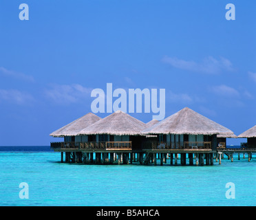 Des bungalows au toit de chaume au-dessus de l'eau dans les îles Maldives Océan Indien Asie Banque D'Images