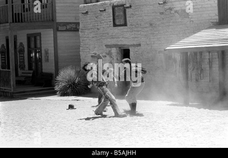 Le point culminant d'une visite à Old Tucson, le célèbre film emplacement dans le désert de l'Arizona, c'est faire l'expérience d'un "live" de coups dans les rues de la ville. Contrairement à la cowboy poussiéreux portant des bottes de daim talon haut et le combattre dehors sur les marches de la Banque mondiale, de l'autre côté de la rue est bordée de touristes vêtus de T-shirts, de sports et de chaussures de tir photos du tireur de combat et le shérif. Juin 1980 Banque D'Images