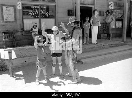 Le point culminant d'une visite à Old Tucson, le célèbre film emplacement dans le désert de l'Arizona, c'est faire l'expérience d'un "live" de coups dans les rues de la ville. Contrairement à la cowboy poussiéreux portant des bottes de daim talon haut et le combattre dehors sur les marches de la Banque mondiale, de l'autre côté de la rue est bordée de touristes vêtus de T-shirts, de sports et de chaussures de tir photos du tireur de combat et sheriff.. Notre photo montre : les enfants avec leurs bras levés de parler avec l'un des cascadeurs. Juin 1980 Banque D'Images