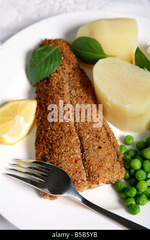 Dans les poissons frits à l'avoine et servi avec des pommes de terre et les pois Banque D'Images