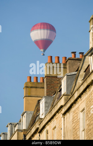 Un rouge et blanc hot air balloon vole au dessus des toits de Bath dans le sud de l'angleterre Banque D'Images