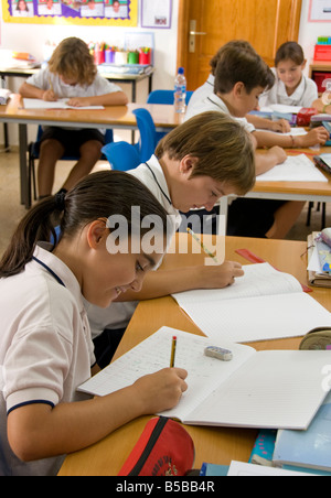 Les enfants de l'école junior 9-11 ans se concentrer sur leur examen écrit à un bureau de classe en classe de l'école Banque D'Images