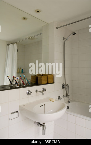 Sol carrelé blanc salle de bains avec baignoire et douche, miroir Banque D'Images