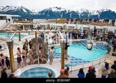 L'homme saute dans une piscine glacée à rejoindre Polar Bear Club alors que les croisiéristes emmitouflés dans des manteaux de human rights watch. Banque D'Images