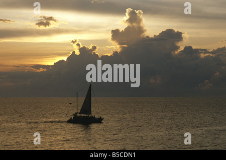 Voilier au coucher du soleil au large de la côte de Negril Jamaïque Banque D'Images