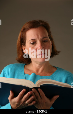 A woman holding et la lecture d'un grand livre de texte Banque D'Images