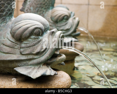 ''Bronze fontaines poisson carpe vaporiser de l'eau dans un étang orné dans une cour publique à Hong Kong." Banque D'Images