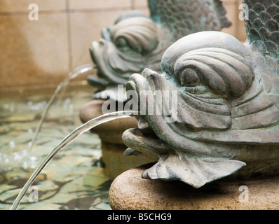 ''Bronze fontaines poisson carpe vaporiser de l'eau dans un étang orné dans une cour publique à Hong Kong." Banque D'Images