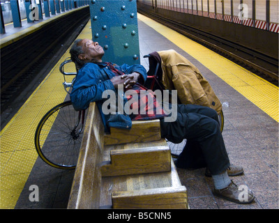 L'homme dort sur plate-forme du métro tard dans la nuit, New York New York USA Banque D'Images