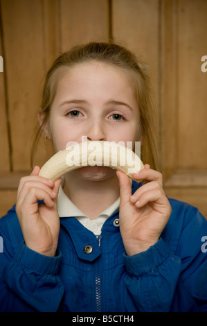 Dix ans, fille triste à la misérable abattu face avec une banane Banque D'Images