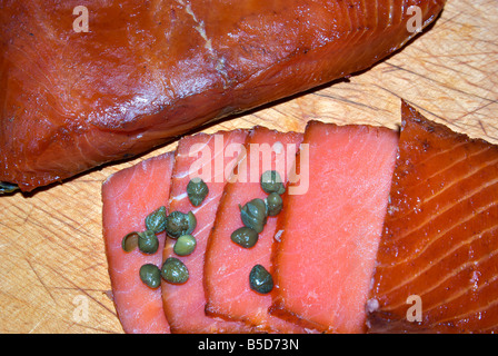 Tranches de sauvages fraîchement fumé du Pacifique roi rouge Saumon quinnat lox aux câpres sur planche à découper en bois Banque D'Images