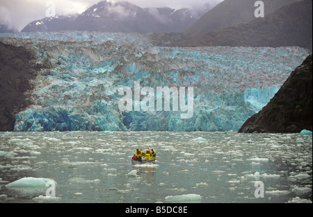 Un petit bateau rempli de passagers d'un navire navigue entre growler tour ci-dessous de la glace massive d'un glacier dans le passage de l'Intérieur, des côtes de l'Alaska. Banque D'Images