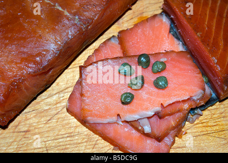 Tranches de fumé du Pacifique sauvages fraîchement roi rouge Saumon quinnat lox aux câpres sur planche à découper en bois Banque D'Images