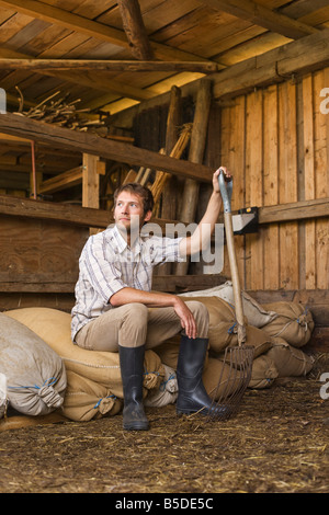 Farmer sitting in barn Banque D'Images