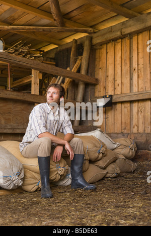 Farmer sitting in barn Banque D'Images