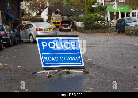 Une "police route fermée" se trouve sur le côté d'une route inondée à Ambleside, Lake District , Royaume-Uni. Banque D'Images