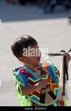 Une jeune Native American Indian boy holding a horse whip cheveux plaqués dans un costume de danse lors d'un Pow-wow au Milwaukee Lakefront Banque D'Images