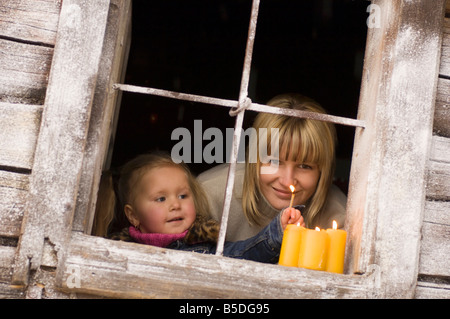 L'Autriche, Salzburger Land, Mère et fille (3-4) l'éclairage candles on windowsill Banque D'Images